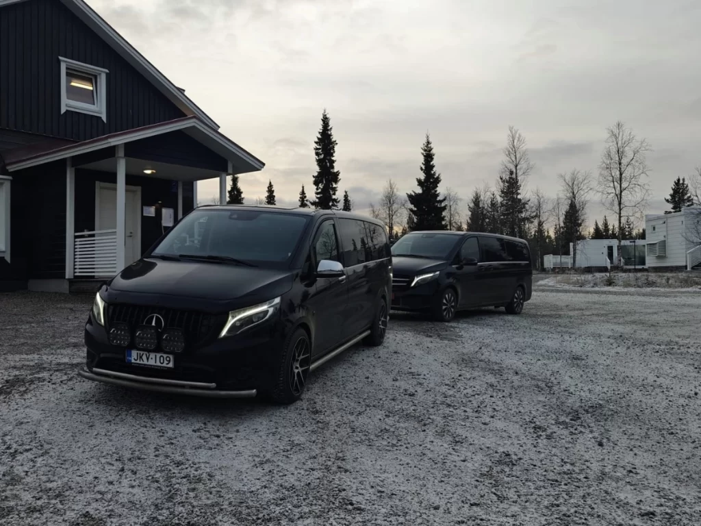 Two private transfer vans parked outside accommodation in Lapland